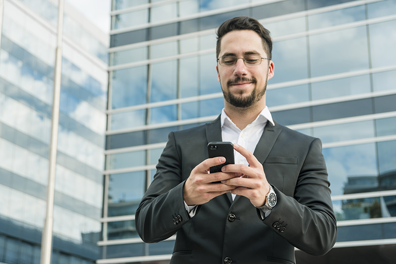 handsome-businessman-enjoying-text-messaging-mobile-phone